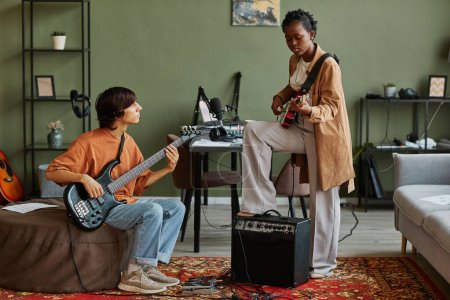 Photo for Full length shot of two young musicians playing guitars together while composing songs in cozy studio - Royalty Free Image