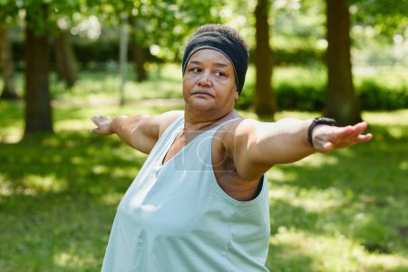 Téléchargez les photos : Portrait taille haute de femme noire en surpoids travaillant à l'extérieur dans le parc et étirant les bras - en image libre de droit
