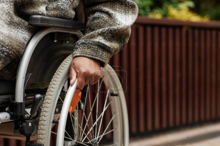 Foto de Primer plano de una mujer negra irreconocible con discapacidad empujando la rueda de la silla de ruedas, espacio para copiar - Imagen libre de derechos