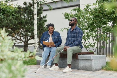 Foto de Retrato de larga duración de pareja adulta con pareja con discapacidad visual sentada en el banco en el parque juntos - Imagen libre de derechos
