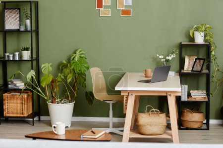 Téléchargez les photos : Image horizontale de la pièce domestique avec plantes vertes et lieu de travail avec ordinateur portable au milieu pour le travail en ligne - en image libre de droit