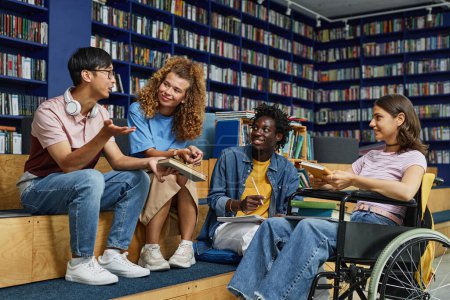Foto de Diverso grupo de estudiantes en la biblioteca universitaria, incluyendo una joven en silla de ruedas disfrutando de la discusión - Imagen libre de derechos