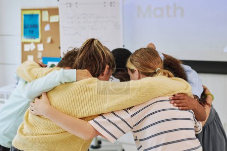 Photo for Diverse group of schoolchildren huddling in team exercise in classroom - Royalty Free Image