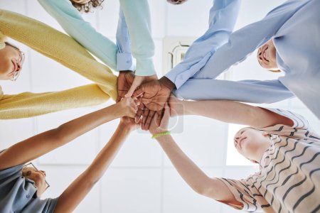 Photo for Low angle view diverse group of children stacking hands and huddling in team exercise - Royalty Free Image