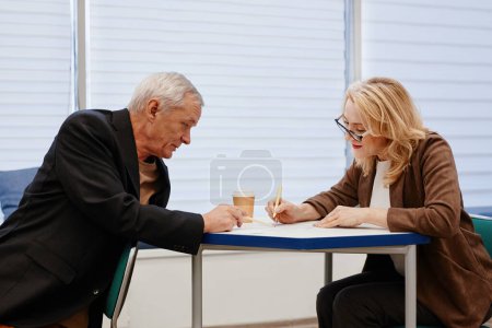 Photo for Senior man asking question to woman while she explaining him new topic during training - Royalty Free Image