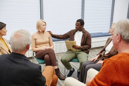Téléchargez les photos : Groupe de personnes assises en cercle et parlant entre elles pendant la thérapie psychologique en classe - en image libre de droit