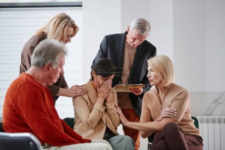 Foto de Grupo de personas mayores que apoyan a la mujer deprimida en problemas mientras está sentada y llorando durante la clase de psicoterapia - Imagen libre de derechos