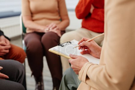 Foto de Primer plano del psicólogo haciendo notas en el documento durante la sesión de psicoterapia con las personas - Imagen libre de derechos