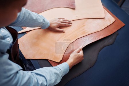Téléchargez les photos : Gros plan de l'artisan travaillant avec des pièces en cuir véritable sur la table dans la tannerie, espace de copie - en image libre de droit