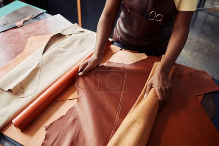 Téléchargez les photos : Vue de dessus gros plan de l'artisan femelle noire travaillant avec du cuir véritable dans l'atelier, espace de copie - en image libre de droit