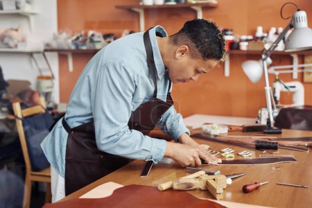Téléchargez les photos : Portrait latéral de l'artisan moderne créant ceinture en cuir faite à la main dans l'atelier, espace de copie - en image libre de droit