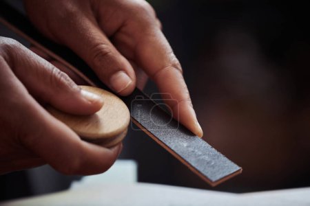 Téléchargez les photos : Macro shot de sablage artisanal méconnaissable pièce en cuir faite à la main dans l'atelier de maroquinerie, espace de copie - en image libre de droit