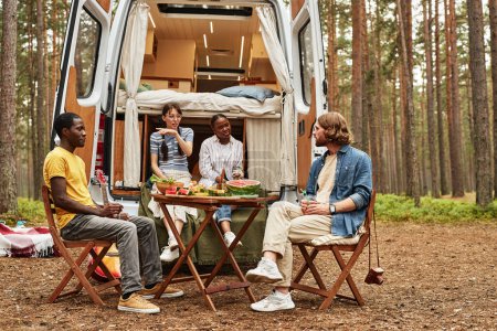 Photo for Young people having picnic in the forest during their camping on house of wheels - Royalty Free Image