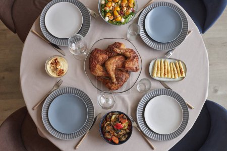 Foto de Vista de ángulo alto de la mesa con pollo frito en el plato con aperitivos y ensalada que sirve para la cena de vacaciones - Imagen libre de derechos