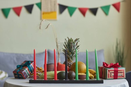 Foto de Imagen horizontal de siete velas con frutas y cajas de regalo en la mesa en la habitación en honor a las vacaciones de Kwanzaa - Imagen libre de derechos