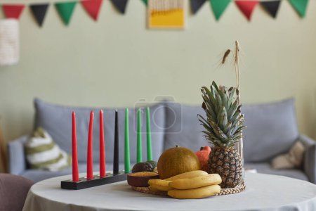 Foto de Imagen horizontal de velas y frutas exóticas para las vacaciones de Kwanzaa en la mesa en la sala de estar - Imagen libre de derechos
