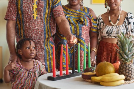 Téléchargez les photos : Gros plan de la famille africaine de quatre bougies brûlantes sur la table ensemble pour les vacances de Kwanzaa - en image libre de droit
