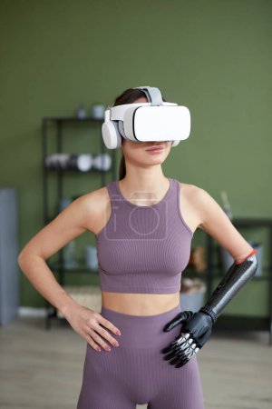 Photo for Young girl in sports clothing doing exercises at home in virtual reality glasses - Royalty Free Image