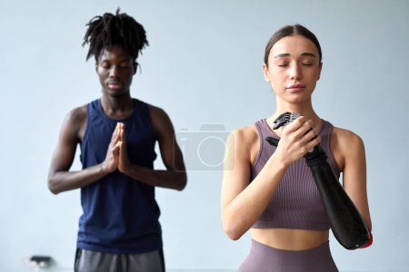 Photo for Young woman with disability meditating with her eyes closed together with young guy during yoga class - Royalty Free Image