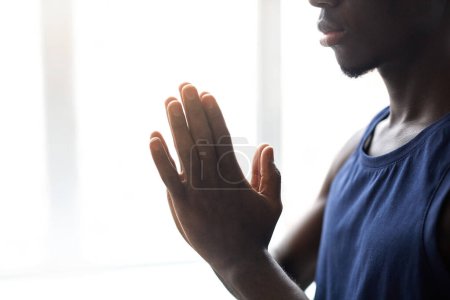 Téléchargez les photos : Gros plan du jeune homme africain pliant les mains et se concentrant sur la méditation pendant la pratique du yoga - en image libre de droit