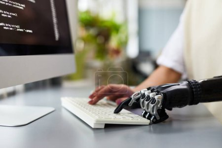 Téléchargez les photos : Gros plan de la femme handicapée tapant au clavier pendant qu'elle travaillait avec un programme d'ordinateur à son lieu de travail - en image libre de droit