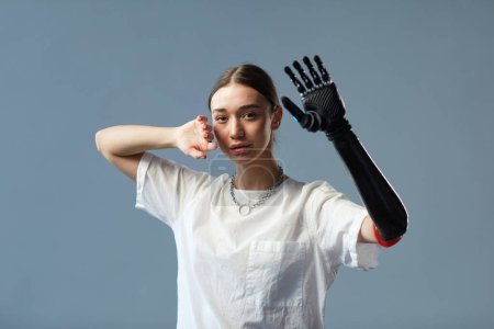 Photo for Portrait of girl with disability with prosthetic arm standing against on blue background - Royalty Free Image