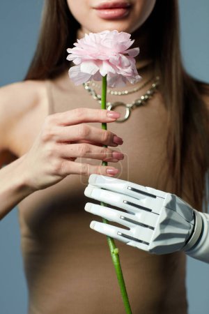 Téléchargez les photos : Gros plan de la jeune fille handicapée tenant de belles fleurs dans ses mains sur fond bleu - en image libre de droit