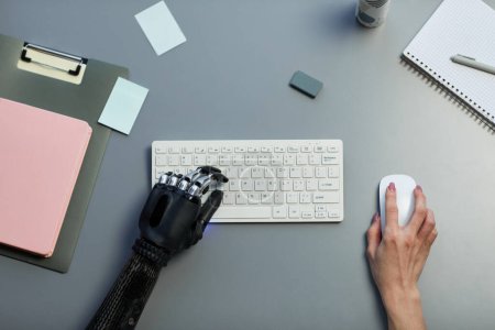 Téléchargez les photos : Vue grand angle de la femme handicapée tapant sur le clavier d'ordinateur sans fil à la table - en image libre de droit