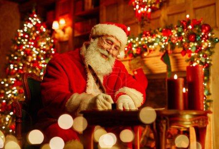 Téléchargez les photos : Portrait du Père Noël traditionnel écrivant lettre par cheminée la veille de Noël et souriant, espace de copie - en image libre de droit