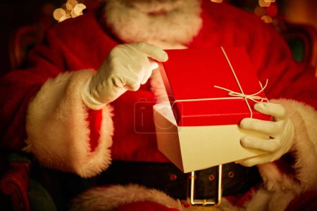 Photo for Close up of traditional Santa Claus opening gift box with magic light inside, copy space - Royalty Free Image