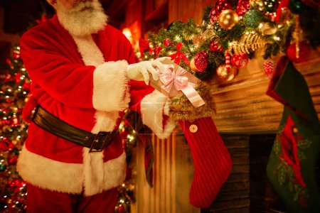 Foto de Tradicional Santa Claus poner presente en las medias sobre la chimenea en Navidad, espacio de copia - Imagen libre de derechos