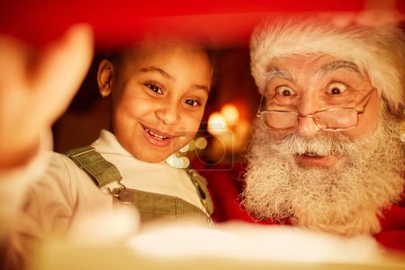 Foto de Fuera de cuadro de tiro de niña linda apertura regalo de Navidad con Santa Claus - Imagen libre de derechos