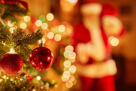Foto de Primer plano de adorno rojo brillante en el árbol de Navidad con Santa en el fondo, espacio de copia - Imagen libre de derechos