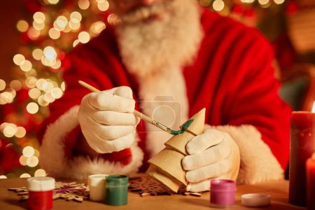 Foto de Primer plano de Santa Claus tradicional pintando juguetes de madera en el taller en la víspera de Navidad, espacio para copiar - Imagen libre de derechos