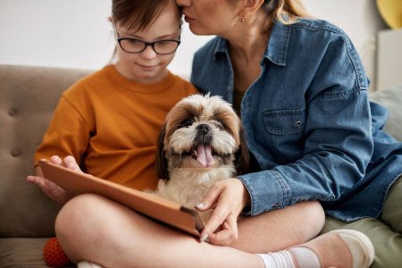 Photo for Portrait of small cute dog sitting on couch with family and looking at camera, copy space - Royalty Free Image