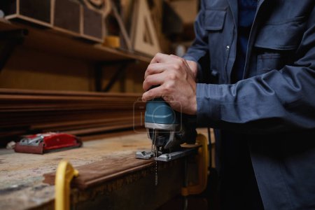 Foto de Primer plano trabajador masculino cortando madera en taller con herramienta eléctrica, espacio de copia - Imagen libre de derechos