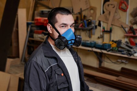 Foto de Retrato del hombre usando respirador en taller de carpintería y mirando a la cámara, espacio para copiar - Imagen libre de derechos