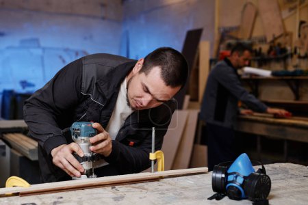 Téléchargez les photos : Portrait d'un ouvrier découpant du bois avec outil électrique dans un atelier d'usine, espace de copie - en image libre de droit