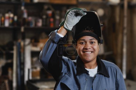 Foto de Retrato de primer plano del soldador femenino sonriente mirando a la cámara en la fábrica industrial, espacio de copia - Imagen libre de derechos