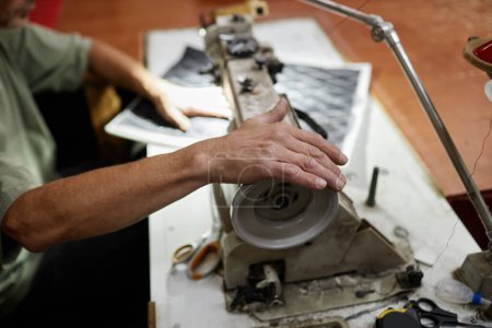 Foto de Primer plano del trabajador masculino que cose el detalle de la tapicería del coche con la máquina de coser industrial en fábrica - Imagen libre de derechos