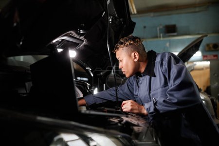 Foto de Retrato de vista lateral del motor del camión de reparación mecánico femenino en el garaje con luz de acento - Imagen libre de derechos