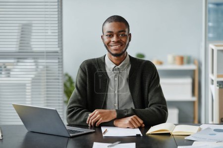 Téléchargez les photos : Vue de face portrait du jeune homme noir souriant à la caméra lors d'un entretien d'embauche - en image libre de droit