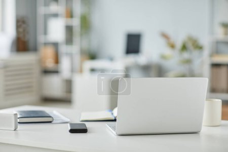 Téléchargez les photos : Image de fond minimale de l'ordinateur portable ouvert sur le lieu de travail dans l'intérieur du bureau dans des tons blancs et gris, espace de copie - en image libre de droit