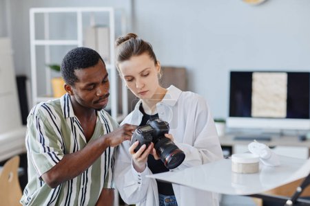 Téléchargez les photos : Portrait de deux photographes prenant des images de produits avec appareil photo professionnel en studio - en image libre de droit