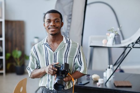 Foto de Retrato de cintura hacia arriba del fotógrafo afroamericano sonriendo a la cámara en el estudio de fotografía, espacio para copiar - Imagen libre de derechos