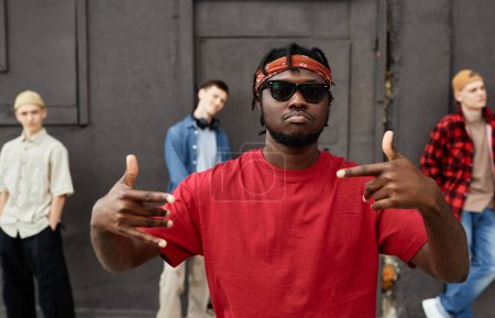 Foto de Diverso equipo de hip-hop contra la pared de hormigón negro, se centran en el hombre afroamericano haciendo gestos de la mano - Imagen libre de derechos