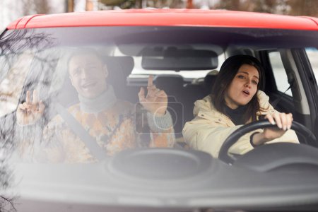 Photo for Portrait of carefree young couple singing in car while driving to winter vacation together - Royalty Free Image