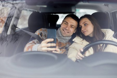 Photo for Portrait of happy adult couple taking selfie in car together and enjoying winter holidays - Royalty Free Image