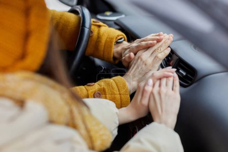 Téléchargez les photos : Gros plan d'un jeune couple gelé essayant de se réchauffer les mains sur un chauffe-voiture, voyageant en hiver - en image libre de droit