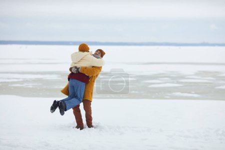 Téléchargez les photos : Portrait complet de jeune couple insouciant embrassant dans un paysage hivernal minimal, espace de copie - en image libre de droit